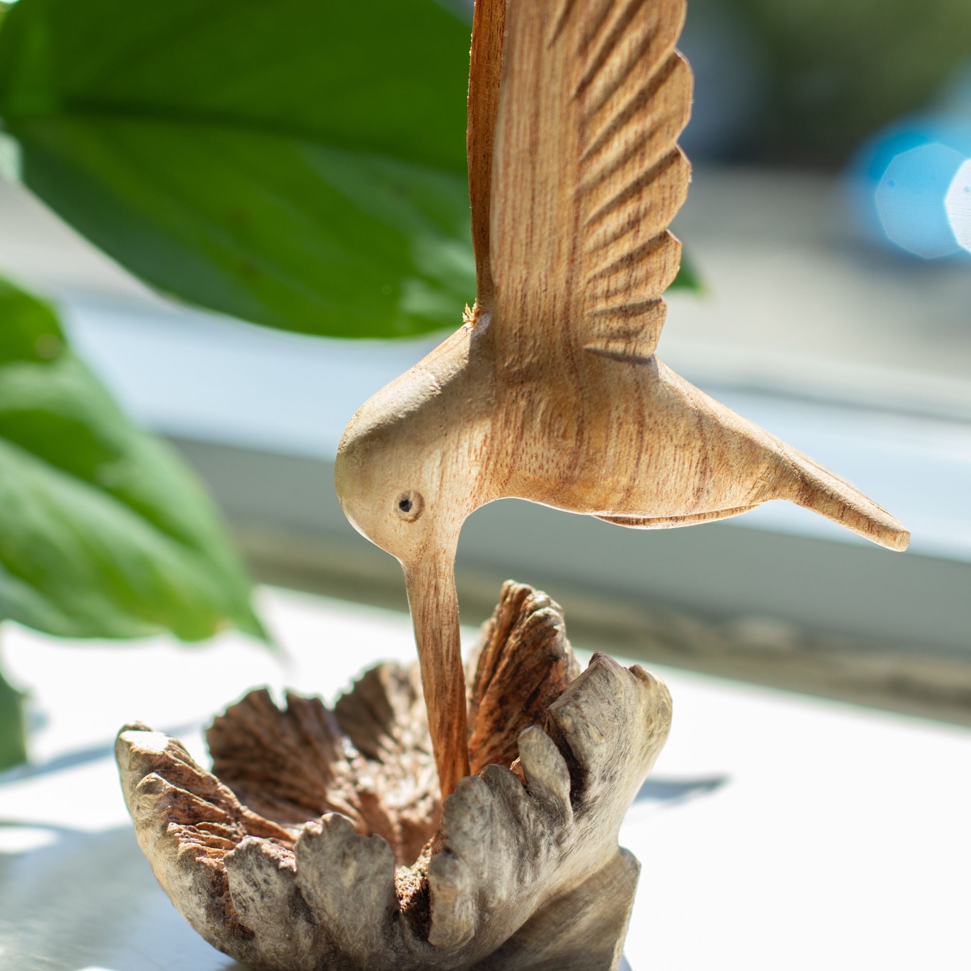 Rankų darbo kolibro skulptūra, geriančio nektarą iš medžio išaugos